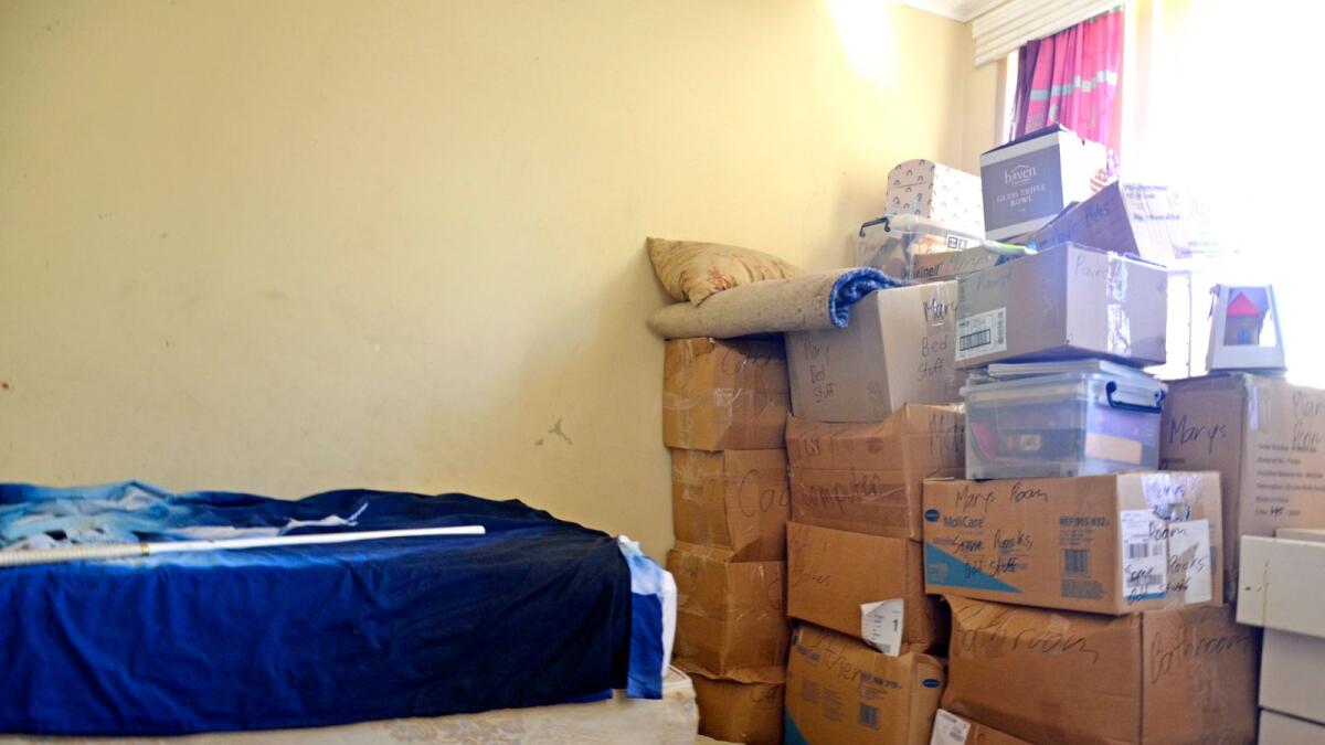 A bed with a pile of cardboard boxes next to it.