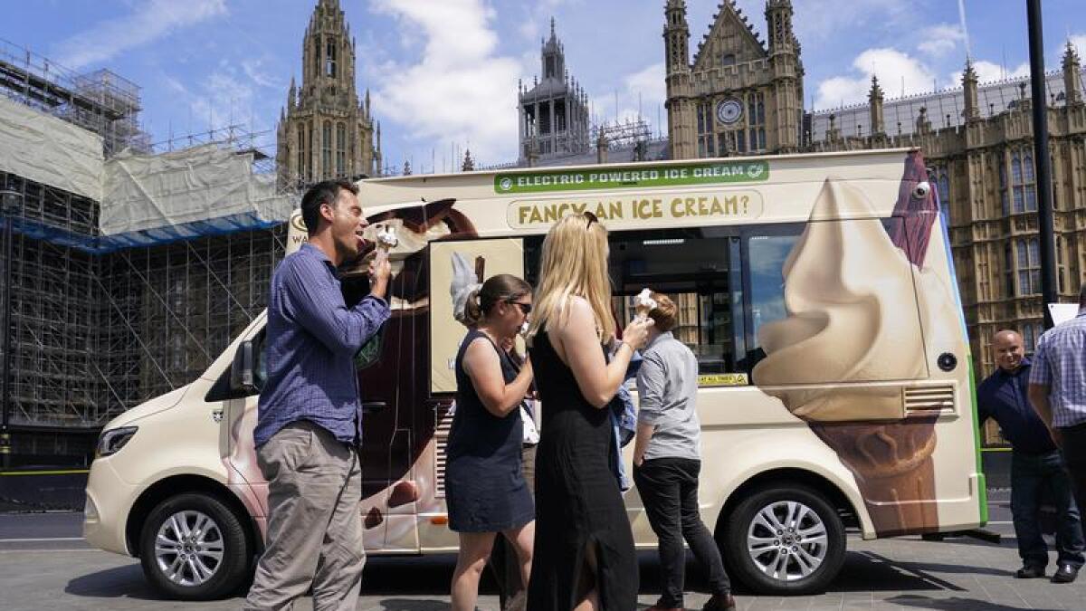 People eat ice cream outside the houses of Parliament, in London.