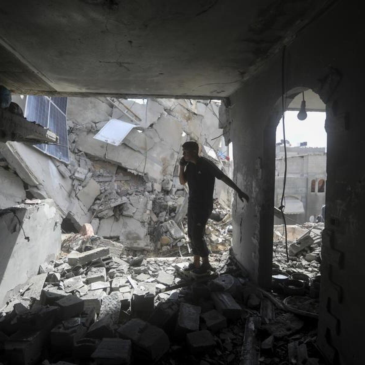 Palestinians look at the destruction after an Israeli strike in Gaza.