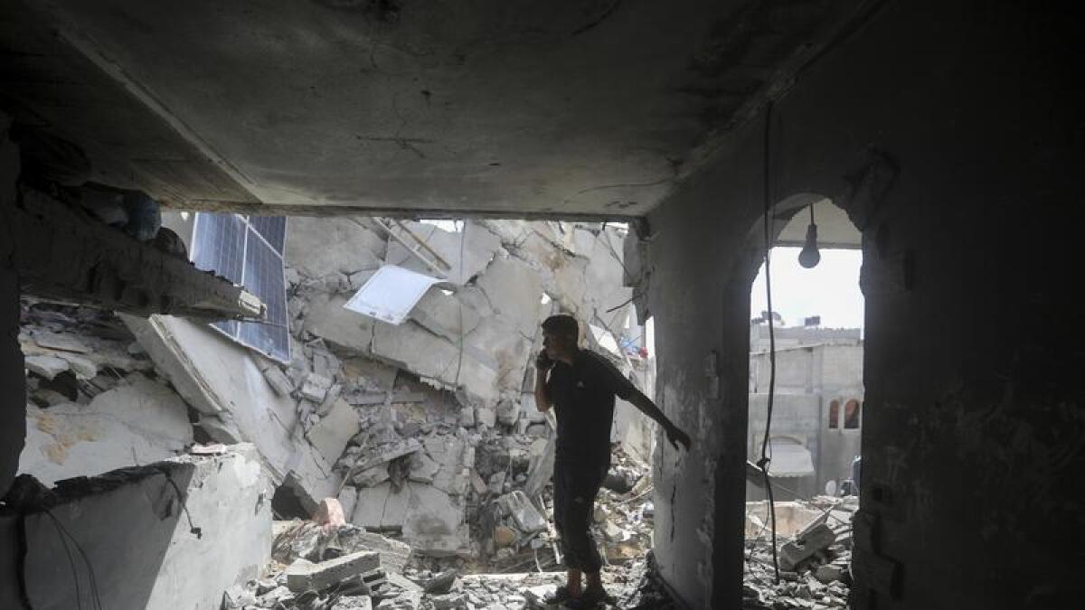 Palestinians look at the destruction after an Israeli strike in Gaza.