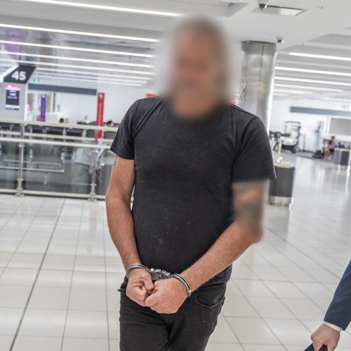 The man is led through Sydney Airport