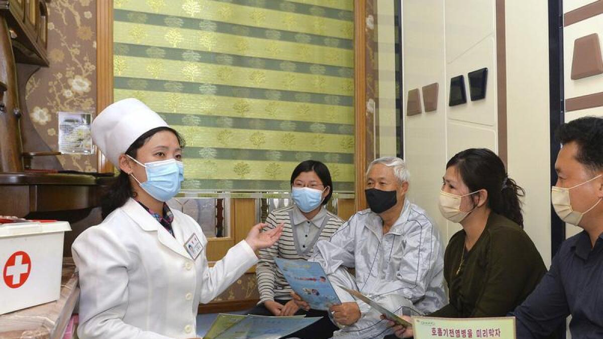 A doctor explains COVID prevention measures to a family in Pyongyang.