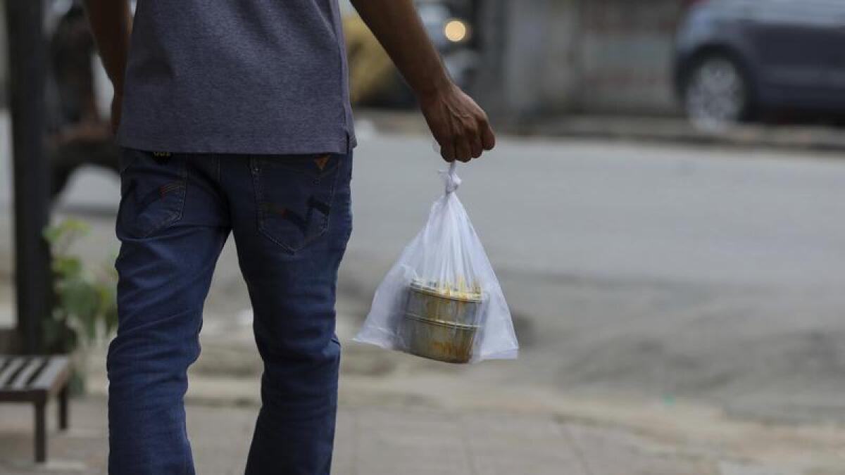 Man carries his tiffin box in a plastic bag