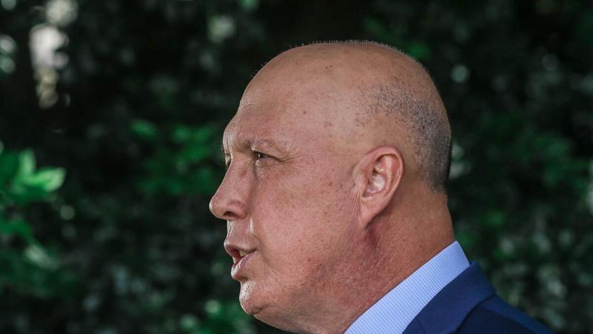 Side profile image of Peter Dutton speaking outside in front of trees.