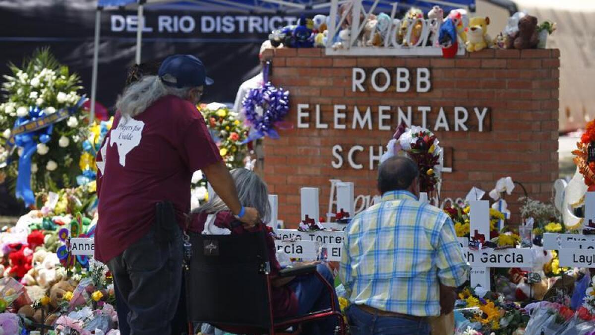 People pay their respects at a memorial outside the school