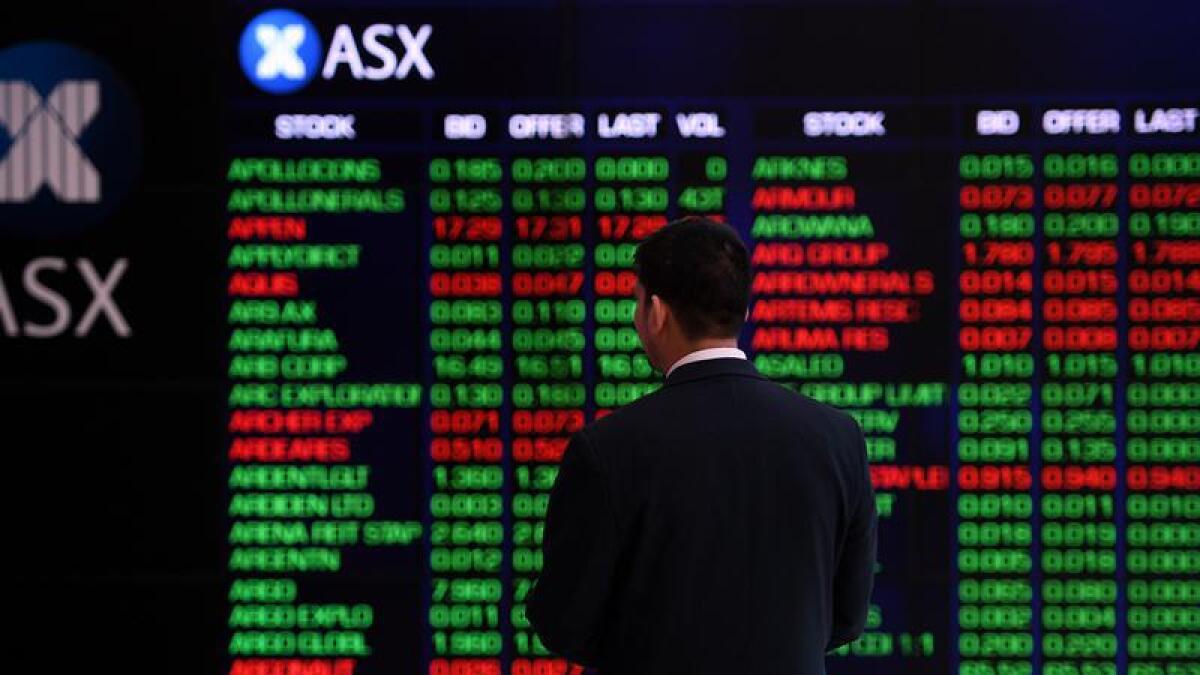A man stands before an ASX trading display.