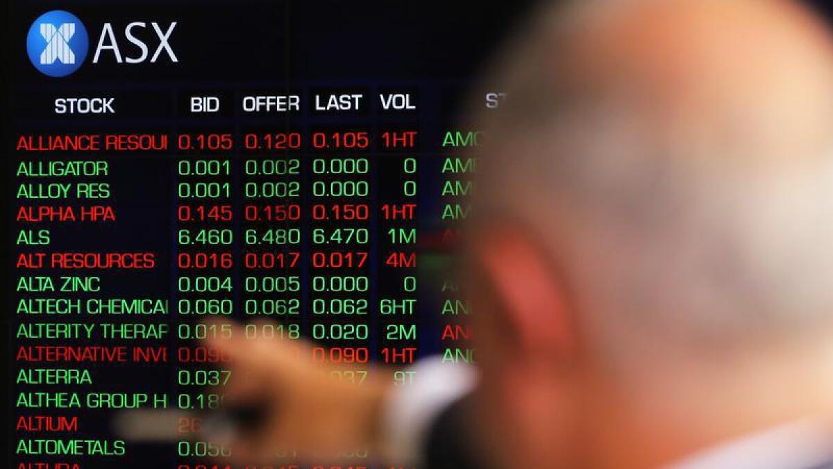 A man points to an ASX trading display.