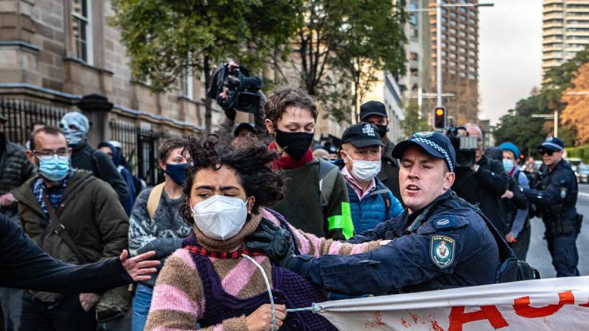 Police officers detain a protester.