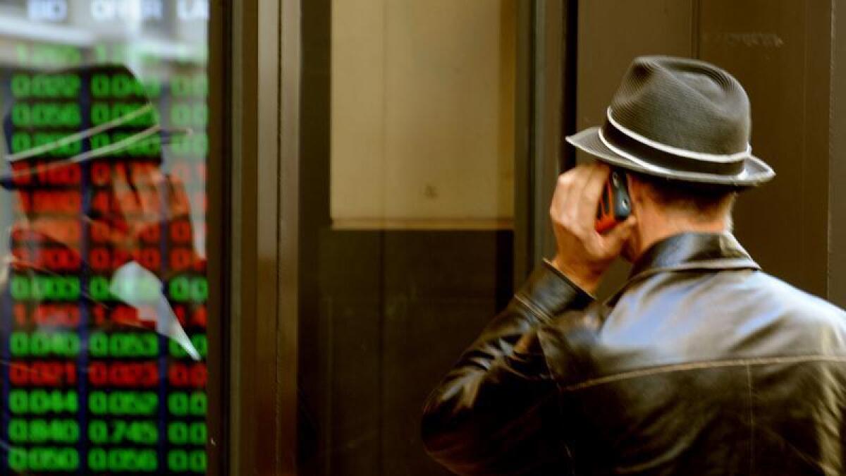 A man looks at an ASX trading display through a window.