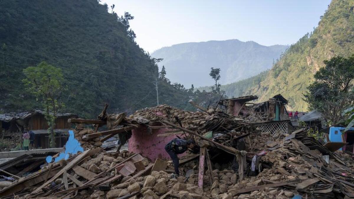 A survivor inspects his earthquake damaged house