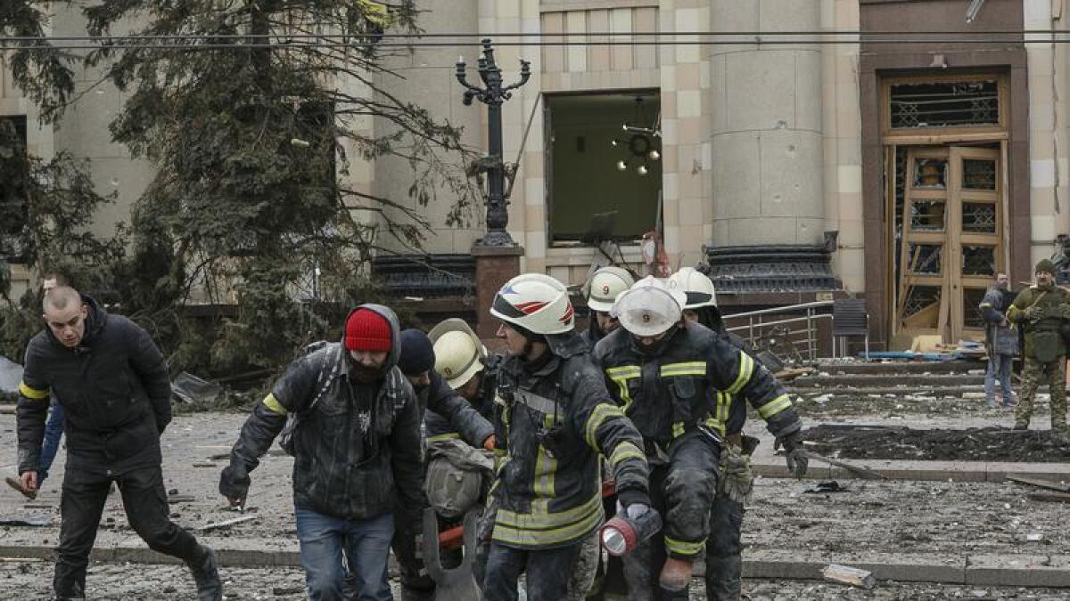 Ukrainian emergency service personnel carry a body in Kharkiv.