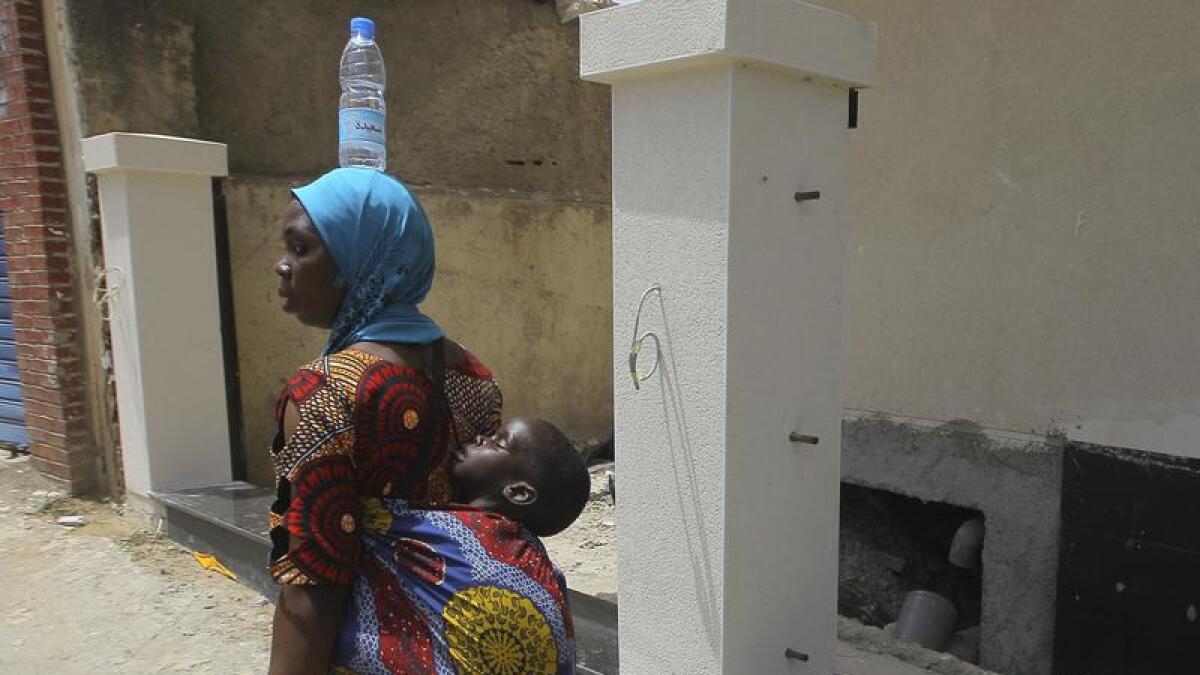 A woman from Niger carries her baby and a bottle of water on her head