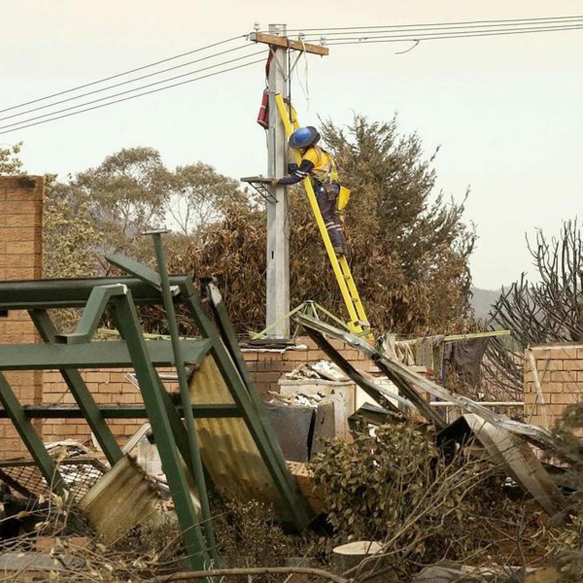 A worker repairs electricity lines following bushfires near Canberra.