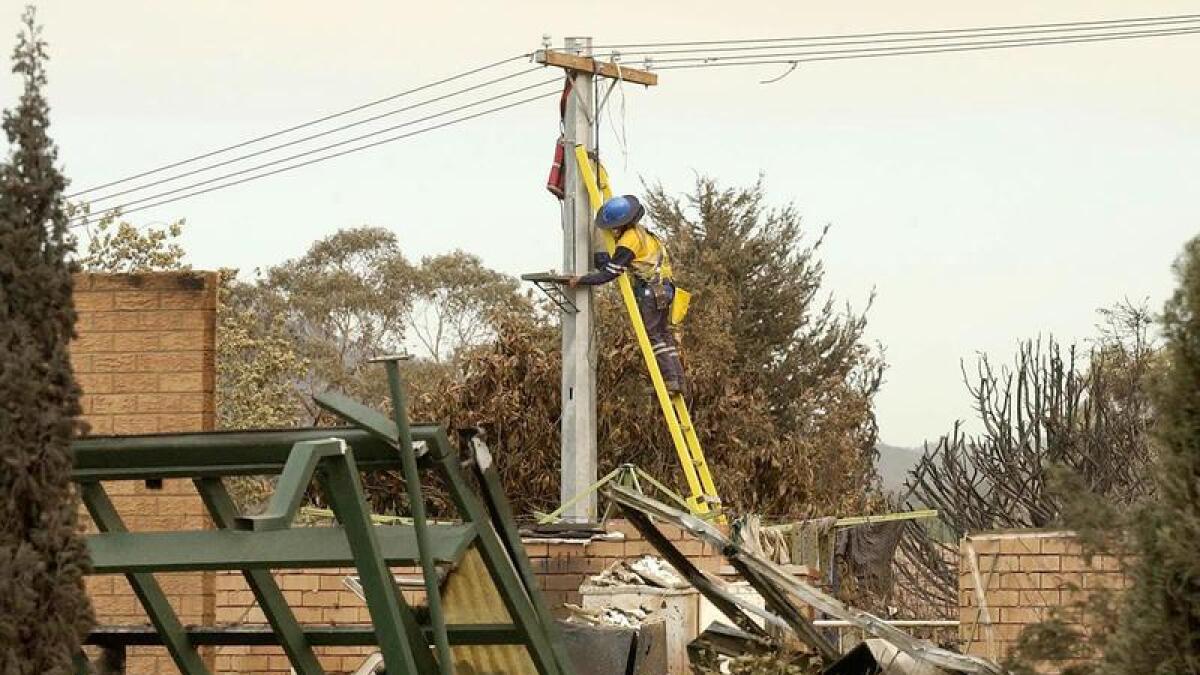 A worker repairs electricity lines following bushfires near Canberra.