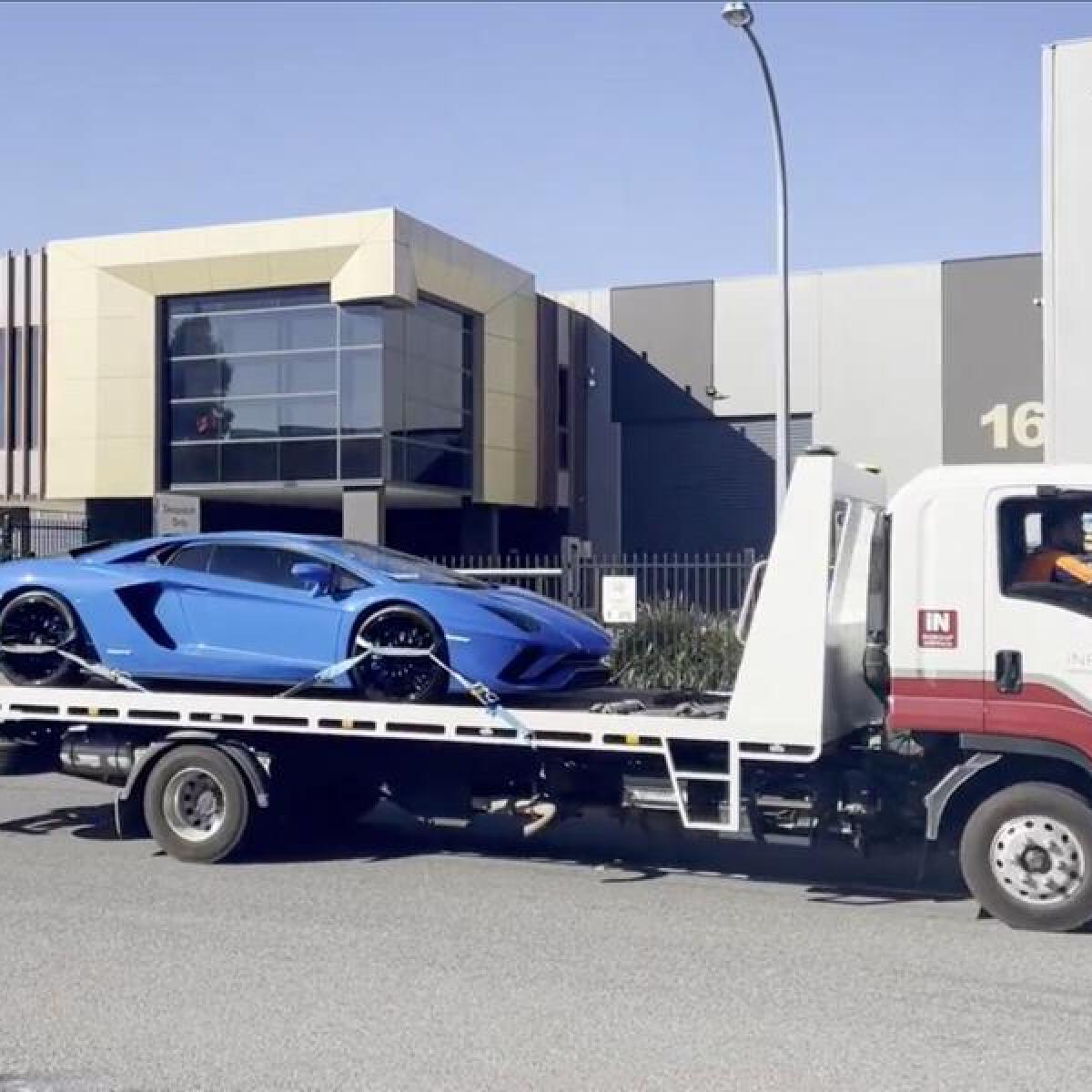 A Lamborghini on the back of a tow truck.