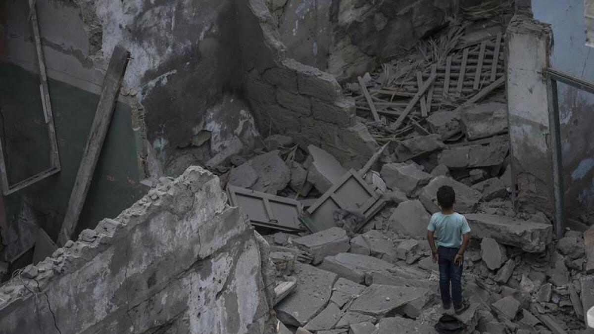 Palestinian boy search stands amidst the rubble of a destroyed house