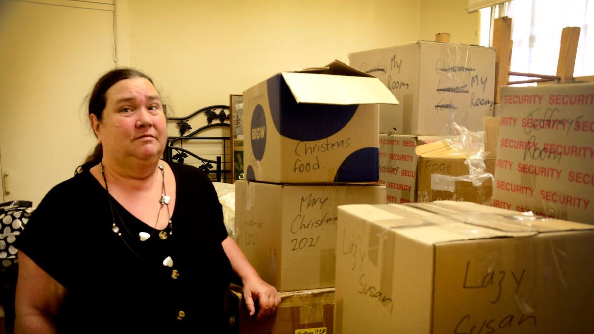 A woman in a black blouse standing surrounded by boxes.