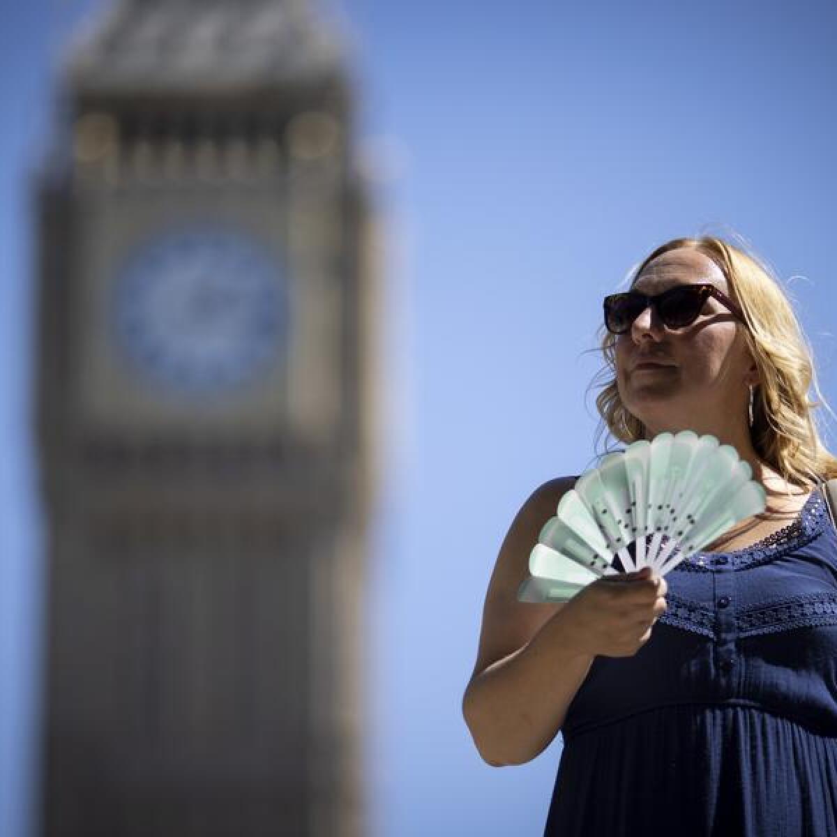 A tourist uses a fan to cool off in Westminster, London, Britain