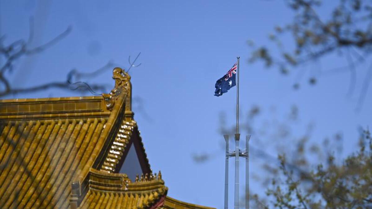 The Australian flag flies behind the roof of the Chinese Embassy.