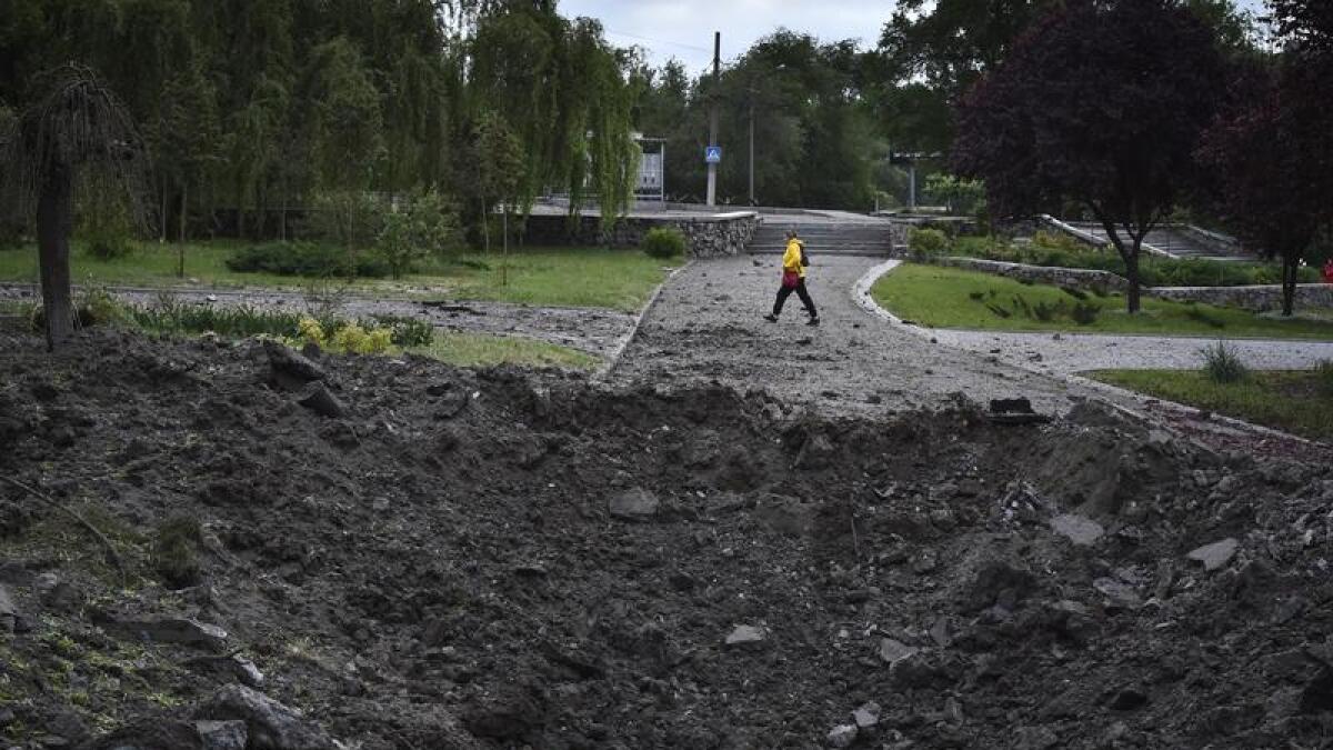 Woman walks by a crater caused by Russian missile in Zaporizhzhia